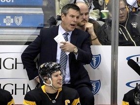 Pittsburgh Penguins head coach Mike Sullivan talks to an official as he stands behind Sidney Crosby (87) during a game against the Los Angeles Kings in Pittsburgh, Saturday, Dec. 15, 2018. (AP Photo/Gene J. Puskar)