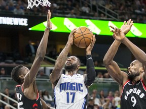 Orlando Magic forward Jonathon Simmons (17) takes the ball up on Toronto Raptors forward Chris Boucher (25) and forward Serge Ibaka (9) during the second half of an NBA basketball game in Orlando, Fla., Friday, Dec. 28, 2018. (AP Photo/Willie J. Allen Jr.) ORG XMIT: DOA109