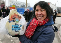 Corinne Wong, who will be donating her turkey to her own charity as the tradition continues for the annual Honest Ed's turkey giveaway, handing out thousands of turkeys at the former site of Honest Ed's at Bloor and Bathurst on Sunday. (Dave Abel/Toronto Sun)