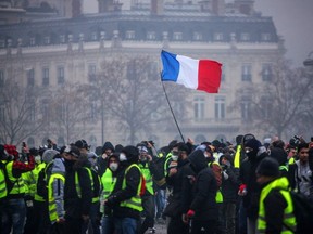 Demonstrators gather near the Arc de Triomphe as a French flag floats during a protest of yellow vests against rising oil prices and living costs, on December 1, 2018 in Paris. (AFP/Getty Images)