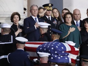 Former President George W. Bush, Laura Bush, left, and other family members watch as the flag-draped casket of former President George H.W. Bush is carried by a joint services military honor guard to lie in state in the rotunda of the U.S. Capitol, Monday, Dec. 3, 2018, in Washington.