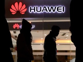 Pedestrians walk past a Huawei retail shop in Beijing Dec. 6, 2018.