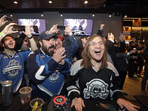 Ryan Kelly, left, Otto Rogers and Rebecca Moloney cheer the announcement of a new NHL hockey team in Seattle at a celebratory party Tuesday, Dec. 4, 2018, in Seattle. (AP Photo/Elaine Thompson)
