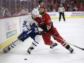 Maple Leafs forward William Nylander (left) is held up by the Carolina Hurricanes' Jaccob Slavin during the first period on Tuesday night in Raleigh, N.C. (Gerry Broome/The Associated Press)