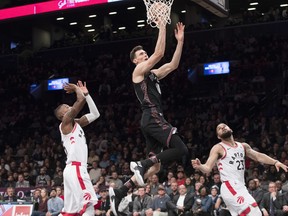 Brooklyn Nets forward Rodions Kurucs (00) goes to the basket past Toronto Raptors guard Fred VanVleet (23) and guard Delon Wright during the second half of an NBA basketball game, Friday, Dec. 7, 2018, in New York. (AP Photo/Mary Altaffer) ORG XMIT: NYMA114