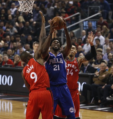 Philadelphia 76ers Joel Embiid C (21) goes up tot the net between Toronto Raptors Serge Ibaka PF (9) and teammate Danny Green SG (14) during the first quarter in Toronto, Ont. on Thursday December 6, 2018. Jack Boland/Toronto Sun/Postmedia Network