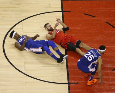 Toronto Raptors Jonas Valanciunas C (17) and Philadelphia 76ers Jimmy Butler SG (23) crash to the court during the fourth quarter in Toronto, Ont. on Thursday December 6, 2018. Jack Boland/Toronto Sun/Postmedia Network