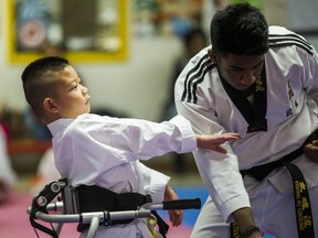 Liam Marriage, 8, with black belt Mayushan Mayurathan, during his taekwondo test for a yellow belt at Variety Village in Toronto, Ont. on Wednesday December 5, 2018. His muscle joint condition – Arthrogryposis multiplex congenita (AMC) – results in all four joints being frozen and stiff. (Ernest Doroszuk/Toronto Sun)