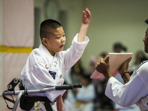Liam Marriage, 8, with black belt Mayushan Mayurathan, during his Taekwondo test for a yellow belt at Variety Village in Toronto, Ont. on Wednesday December 5, 2018. His muscle joint condition – Arthrogryposis multiplex congenita (AMC) – results in all four joints being frozen and stiff. (Ernest Doroszuk/Toronto Sun)