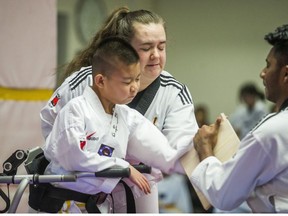 Liam Marriage, 8, with black belts Kelly Morrison (back) and Mayushan Mayurathan, during his taekwondo test for a yellow belt at Variety Village in Toronto, Ont. on Wednesday December 5, 2018. His muscle joint condition — Arthrogryposis multiplex congenita (AMC) – results in all four joints being frozen and stiff. (Ernest Doroszuk/Toronto Sun/Postmedia)