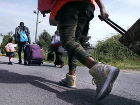 Wearing her gold high-stop sneakers, Lena Gunja, 10, originally from Congo and who had been living in Portland, Maine, follows her family as they approach an unofficial border crossing with Quebec while walking down Roxham Road in Champlain, N.Y., Monday, Aug. 7, 2017. "In Trump's country they want to put us back to our country," said Gunja. "So we don't want that to happen to us so. We want a good life for us. My mother, she wants a good life for us." (AP Photo/Charles Krupa) ORG XMIT: NYCK105