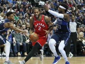 Raptors forward Kawhi Leonard drives between Dallas Mavericks guards Wesley Matthews (left) and Dennis Smith Jr. during Sunday's game. (AP PHOTO)