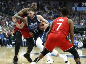 Dallas Mavericks forward Luka Doncic drives between Raptors' Serge Ibaka (left) and Kyle Lowry during Sunday's game. (AP PHOTO)