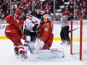 Canada's Maxime Comtois (14) bumps into Russia goalie Pyotr Kochetkov (20) after the puck deflected wide of the goal while Russia's Alexander Romanov (left) defends during world junior championship action in Vancouver on Monday, Dec. 31, 2018. (THE CANADIAN PRESS)