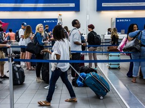 Travelers wait in line at the Delta Air Lines ticket counter inside LaGuardia Airport in New York. Bloomberg photo by David Williams