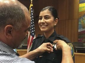 This Aug. 2, 2018 photo provided by Williams Pioneer Review shows Merced Corona, left, pins his daughter Natalie Corona's badge on her uniform during a swearing-in ceremony in Davis, Calif.