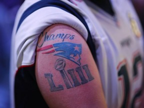 A New England Patriots fan walks in the fan area during Opening Night for the NFL Super Bowl 53 football game Monday, Jan. 28, 2019, in Atlanta.