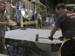 In this Tuesday, Jan. 8, 2019 photo, stone cutters Evan Ladd, left, and Andy Hebert cut a piece of granite at Rock of Ages in Barre, Vt. The granite will be formed into stone monoliths that will be part of a permanent dedication to ground zero rescue and recovery workers expected to be unveiled in late May at the National September 11 Memorial & Museum in New York.
