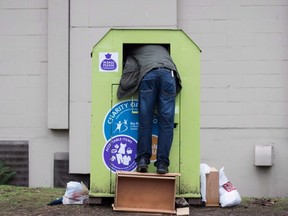 A man tries to retrieve items from a clothing donation bin in Vancouver on December 12, 2018.  THE CANADIAN PRESS/Darryl Dyck
