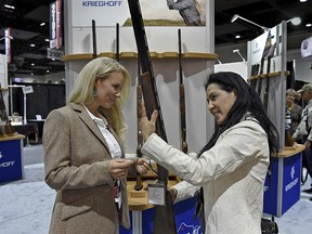 In this Wednesday, Jan. 9, 2019, photo, Rachel Carrie, left, with Krieghoff International, shows Gladys Taggart a Krieghoff K-20 Victoria shotgun designed for women at the SCI Convention at the Reno-Sparks Convention Center in Reno, Nev. (Andy Barron/The Reno Gazette-Journal via AP)
