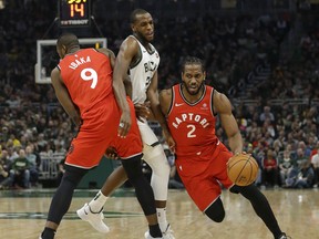 Raptors’ Kawhi Leonard (right) drives to the basket against Bucks’ Khris Middleton during the first half on Saturday night in Milwaukee. (AP PHOTO)