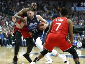 Dallas Mavericks forward Luka Doncic (77) drives between Toronto Raptors center Serge Ibaka, left, and guard Kyle Lowry (7) during the second half of an NBA basketball game in Dallas, Sunday, Jan. 27, 2019.  (AP Photo/LM Otero)