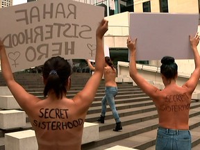 In this image made from video, woman protesters march with a sign outside the building housing the Saudi consulate in Sydney, Thursday, Jan. 10, 2019.