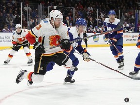 Sam Bennett of the Calgary Flames is bumped by Thomas Hickey of the New York Islanders during the third period at NYCB Live's Nassau Coliseum on February 26, 2019 in Uniondale, New York.