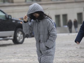 A woman makes her way thorugh the wind and freezing rain on Bay St. on Wednesday. (Stan Behal, Toronto Sun)