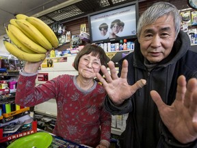 Sung-Ae Kim (L) holds a bunch of bananas like the ones she swung at a robber. Her husband, Ik-Soo Kim, shows how he pushed the robber, p;reventing him from climbing over the counter. (Craig Robertson, Toronto Sun)