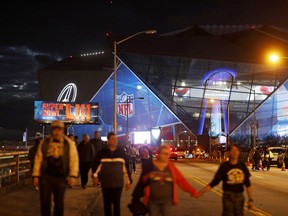 Pedestrians walk in front of Mercedes-Benz Stadium ahead of Sunday's NFL Super Bowl 53 football game between the Los Angeles Rams and New England Patriots in Atlanta, Saturday, Feb. 2, 2019. (AP Photo/David Goldman)