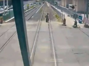A pedestrian can be seen crosses the tracks as a GO Transit train barrels down on them in September.