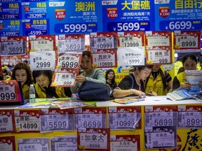 In this March 3, 2018, photo, people check on travel packages offered by travel agencies during the Guangzhou International Travel Fair in Guangzhou in south China's Guangdong province. (Chinatopix via AP)