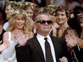 In this July 20, 1993 filer, German fashion designer Karl Lagerfeld acknowledges the applause of his models at the end of the show he designed for the French fashion house Chanel, for the 1993-94 Fall-Winter haute couture collection in Paris, July 20, 1993. At left background is German top model Claudia Schiffer. Chanel's iconic couturier, Karl Lagerfeld, whose accomplished designs as well as trademark white ponytail, high starched collars and dark enigmatic glasses dominated high fashion for the last 50 years, has died. He was around 85 years old.