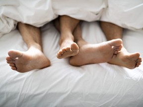 A two pairs of feet under duvet couple makes love in bed
