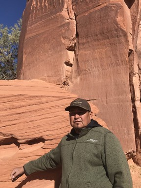 Navajo guide Harold Bia poses in front of ancient pictographs in the Canyon de Chelly National Monument that will eventually be lost to wind and rain because the sandstone is so soft on the canyon cliff wall. (Kim Pemberton photo)