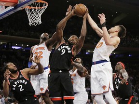 Raptors' Serge Ibaka (9) rebounds as New York Knicks' Noah Vonleh (32) and Kevin Knox (20) fight for control of the ball during the second half in New York last nigt.  The Raptors won 104-99. (AP Photo/Frank Franklin II)