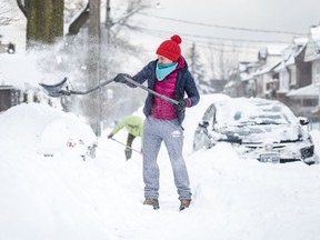 People shovel snow from the sidewalk after a heavy snowstorm in Toronto on Jan. 29, 2019.