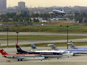 A plane makes its final approach as other planes are parked on the tarmac at Pearson International Airport in Toronto. (THE CANADIAN PRESS/Frank Gunn)