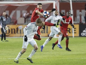 Toronto FC midfielder Jonathan Osorio brings down a ball in front of New England Revolution midfielder Scott Caldwell on Sunday. (THE CANADIAN PRESS)