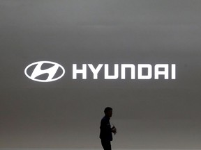 In this March 28, 2019, file photo a journalist passes by the logo of Hyundai Motor during a media preview of the Seoul Motor Show in Goyang, South Korea. (AP Photo/Ahn Young-joon, File)