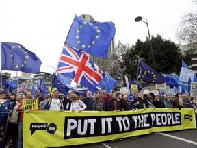 Demonstrators hold a banner during a Peoples Vote anti-Brexit march in London, Saturday, March 23, 2019.