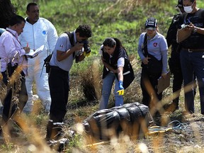 Forensic experts work in the recovery of bodies wrapped in bags found in a blackwater river channel in Ixtlahuacan de los Membrillos, Jalisco state, Mexico, on March 14, 2019. (ULISES RUIZ/AFP/Getty Images)