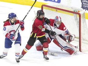 Calgary Inferno's Rebecca Leslie (centre) tries to tip the puck past Les Canadiennes de Montreal's goaltender Emerance Maschmeyer on Sunday. (The Canadian Press)