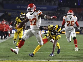 In this Nov. 19, 2018, file photo, Kansas City Chiefs running back Kareem Hunt scores a touchdown ahead of Los Angeles Rams free safety Lamarcus Joyner as Chiefs offensive guard Cameron Erving (75) looks on during the first half of an NFL football game, in Los Angeles.