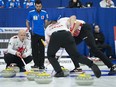Canada skip Kevin Koe calls for the sweep as Italy lead Simone Gonin looks on at the world men's curling championship in Lethbridge, Alta. on Sunday, March 31, 2019.