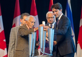 Along with holocaust survivors Joe Gottdenker (2nd from right) and Victor David (2nd left), 2nd and 3rd generation survivors Lou Greenbaum (slightly hidden on left) and Kyle Goldenberg (behind menorah), Prime Minister Justin Trudeau helps light the first candle at the Canadian War Museum during ceremonies marking the National Holocaust Remembrance Day in 2016. (Wayne Cuddington)