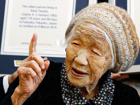 Kane Tanaka, a 116-year-old Japanese woman, gestures after receiving a Guinness World Records certificate, back, at a nursing home where she lives in Fukuoka, southwestern Japan, Saturday, March 9, 2019.
