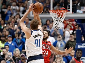 Dallas Mavericks forward Dirk Nowitzki shoots as New Orleans Pelicans' Kenrich Williams defends and Pelicans' Julius Randle and Anthony Davis watch in the first half of an NBA game in Dallas, Monday, March 18, 2019. With the basket, Nowitzki became the NBA's sixth-leading scorer.