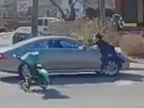 A woman climbs on the hood of a Mercedes after nearly being hit crossing a Toronto road with a baby in a stroller. (YouTube screengrab)